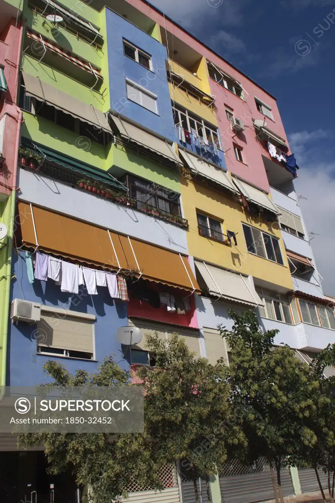Albania, Tirane, Tirana, Part view of exterior facade of multi coloured apartment block with washing hanging from balconies beneath pulled out awnings.