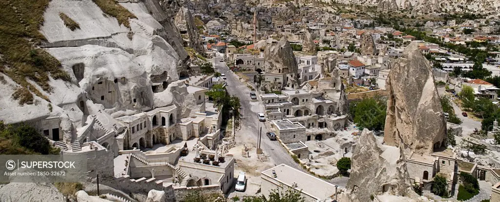 Turkey, Cappadocia, Goreme, Cave hotel with a section of the town and its minaret.