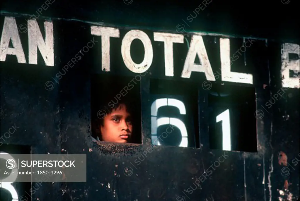 Sri Lanka, Kandy , Young Boy Peering Out Through Cricket Scoreboard To Watch Game