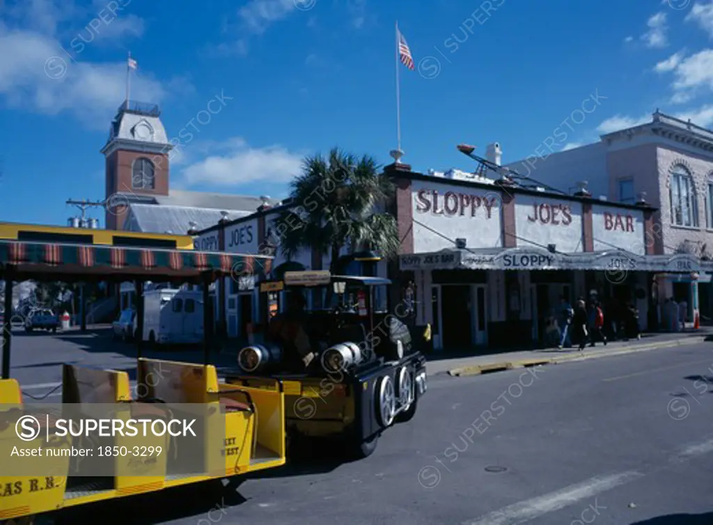 Usa, Florida,  Key West , Duval Street. Sloppy Joes Bar And Tourist Train Traveling Along Road