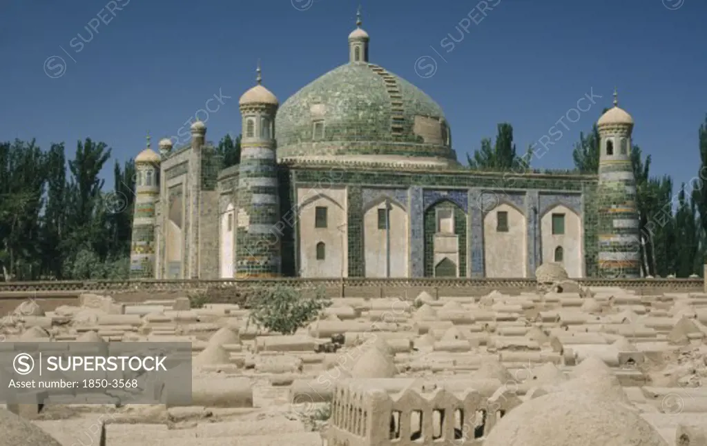 China, Xinjiang, Kashgar , Abakh Hoja Tomb Burial Place Of Hidajetulla Hoja And His Decendants. Domed Building With Green Tiles Viewed Across A Dusty Graveyard