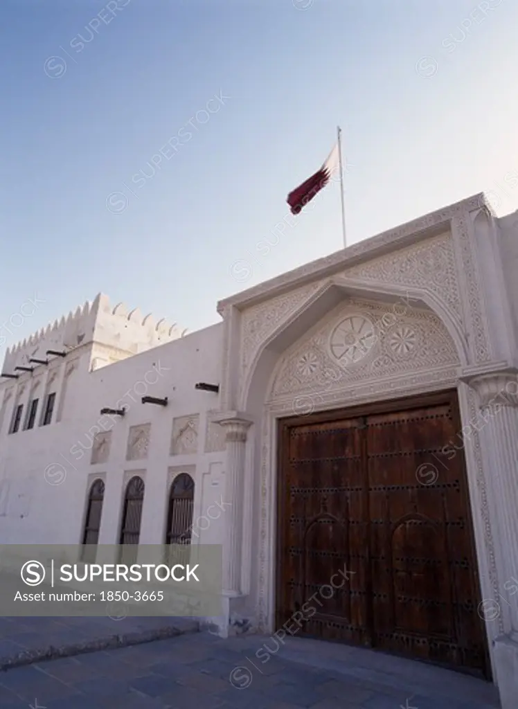 Qatar, Doha, Doha Fort.  Exterior View Showing Ornate Doors With The Qatar Flag Flying Above.