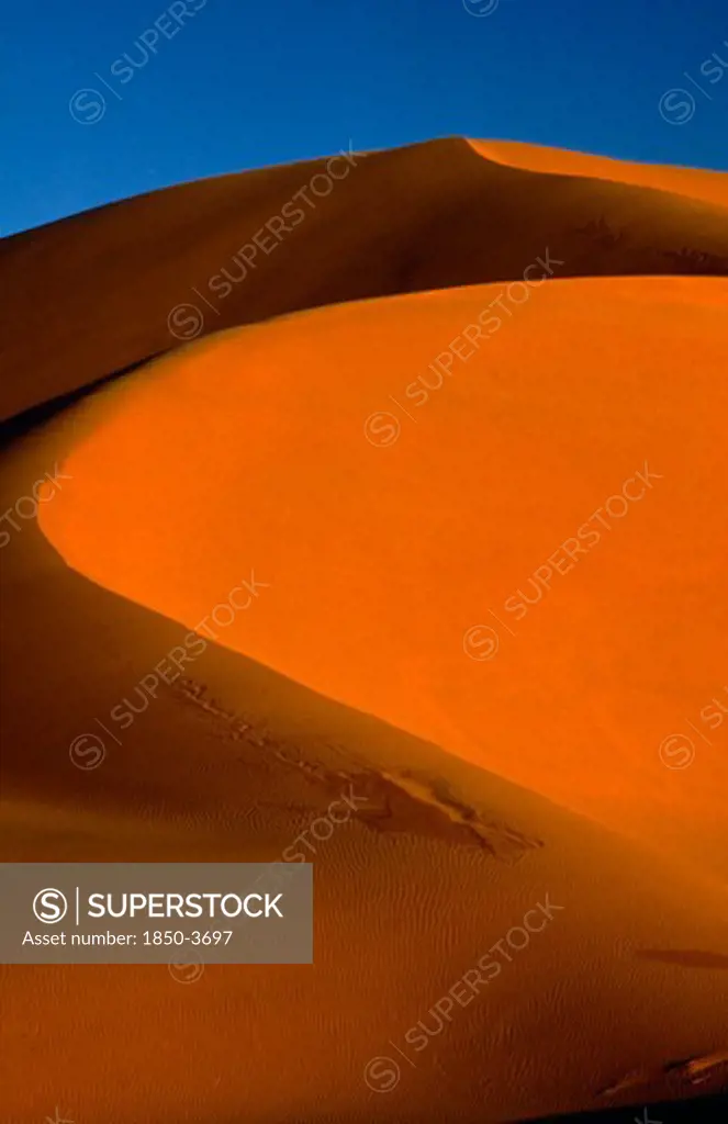 Libya, South West , Achan , Orange Desert Sand Dune Against A Clear Blue Sky