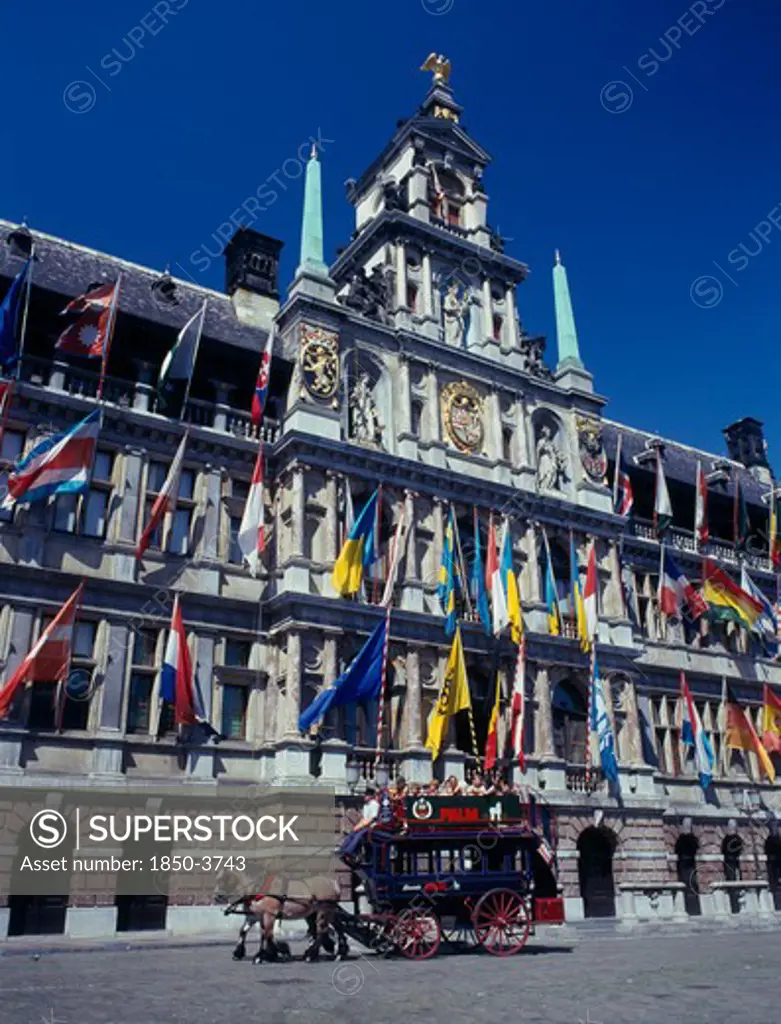 Belgium, Flemish Region, Antwerp, A Horse Drawn Tourist Coach In Front Of The Town Hall Which Is Covered In Flags.