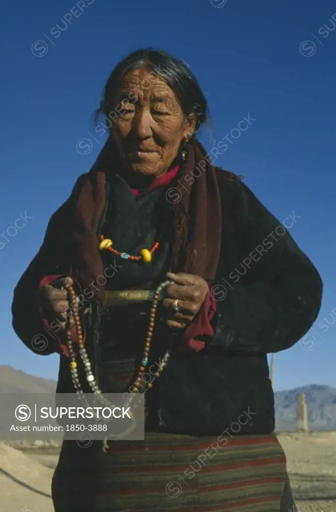 China, Tibet, Shalu Monastery. Pilgrim Holding Prayer Beads.  Three-Quarter Portrait.
