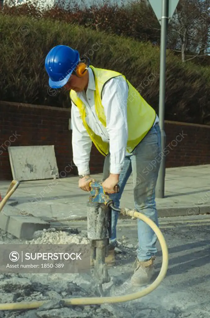 Architecture, Construction, Workers, Man Wearing Ear Protection Helmet And Goggles Using Pneumatic Drill In The Road