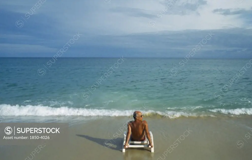 Thailand, Surat Thani, Koh Samui, Lamai Beach With Lone Male Tourist Sitting On A Sunbed On The Empty Beach