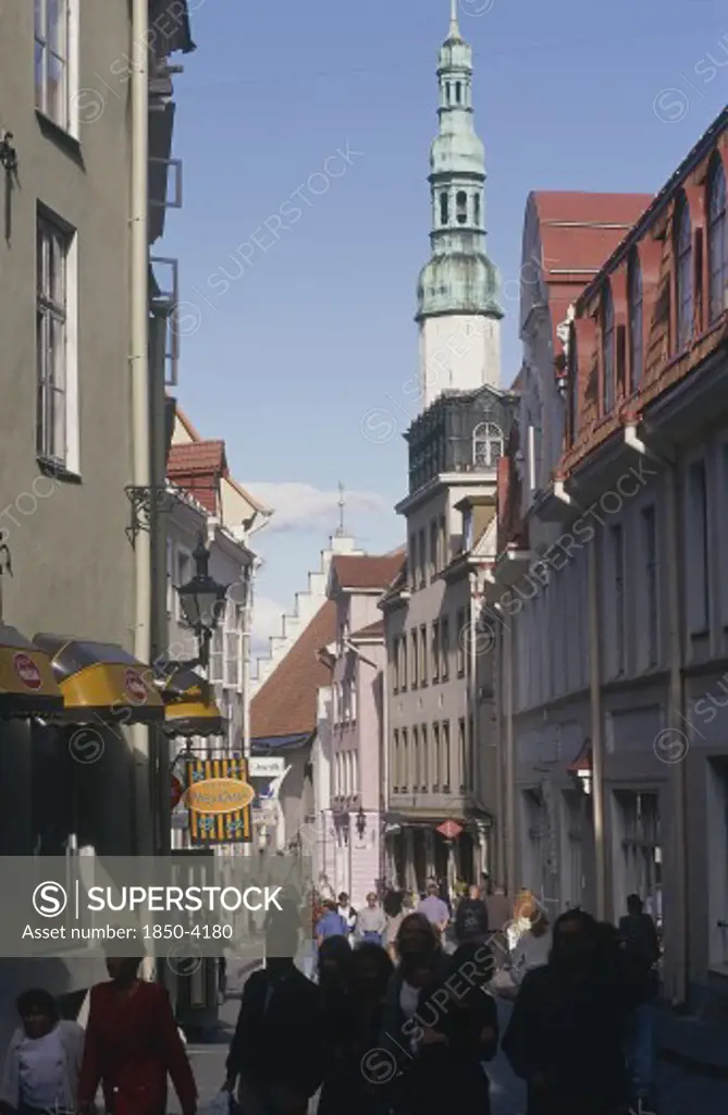 Estonia, Tallinn, Shops And A Church With A Tower In A Street In The Old Town Busy With Pedestrians