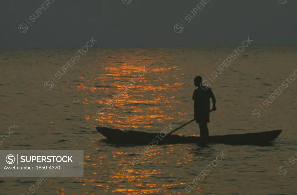 Tanzania, Lake Tanganyika, Mokoro Canoe Raft Paddler On Water At Sunset
