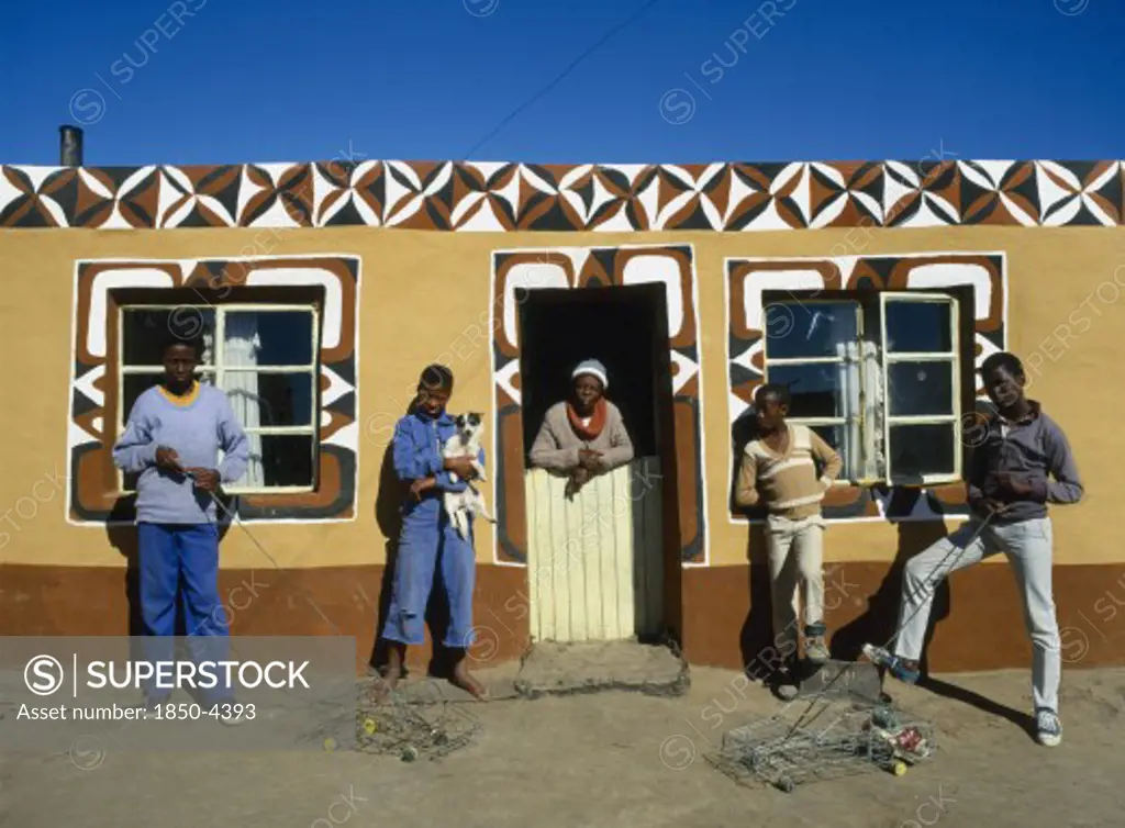 South Africa, Tribal Peoples, Basotho Family Outside Typical Painted Home. Young Boys With Model Toy Cars.