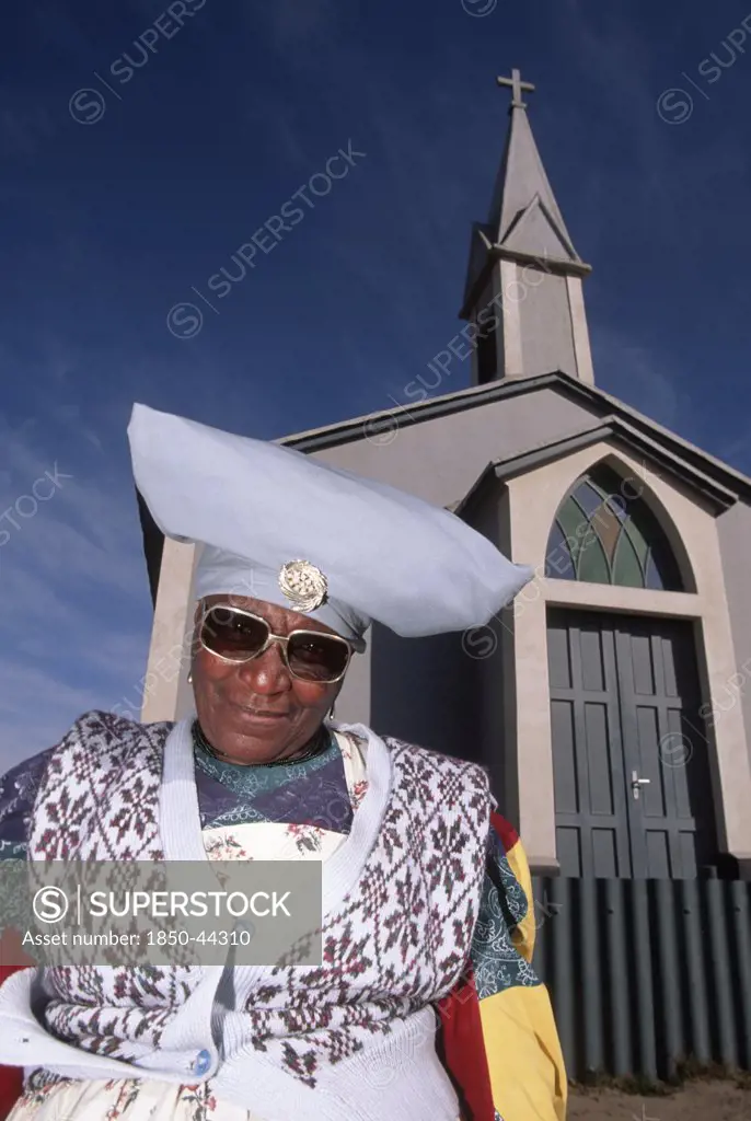 Namibia ,  Mondesa, Herero woman in Mondesa the township of Walvis Bay Namibia standing next to a Presbytarian church.