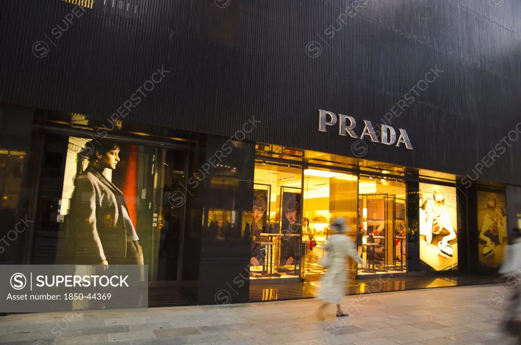 Japan, Honshu, Tokyo, Ginza shopper walking by the Prada store on Chou-dori Avenue.