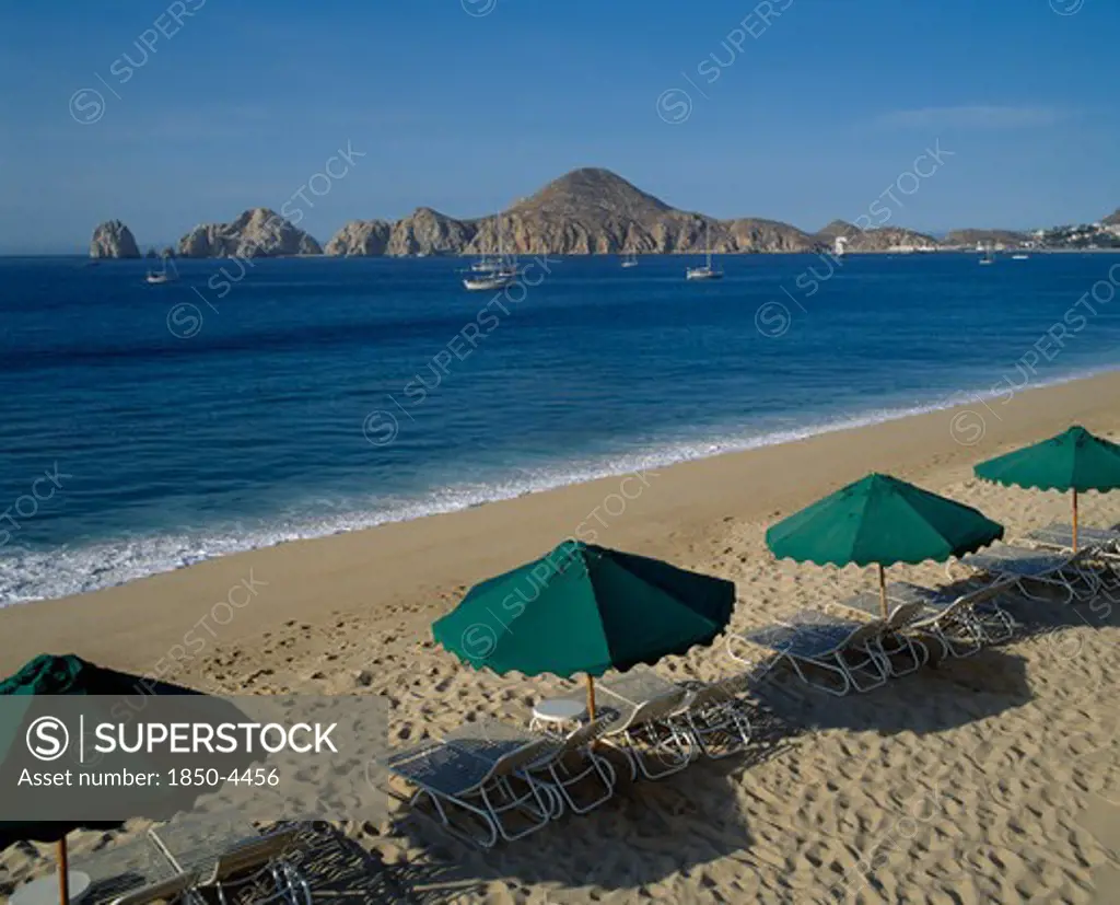 Mexico, Baja California, Cabo San Lucas, Menano Beach Area View Over Beach To Surrounding Coastline Sun Longers & Shades In Foreground
