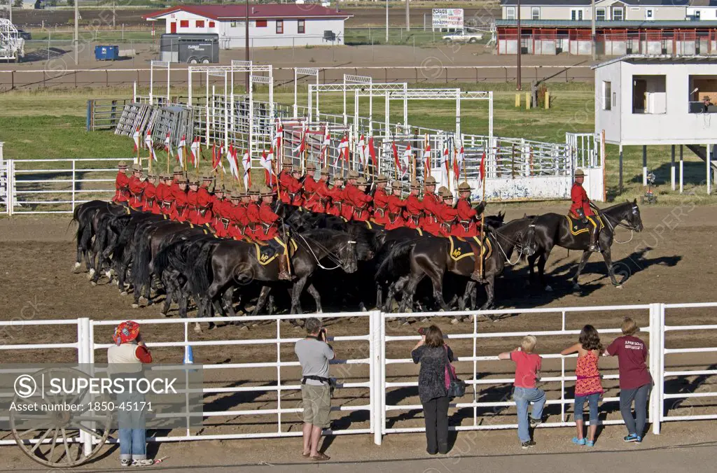 Royal Canadian Mounted Police Musical Ride 32 RCMP cavalry in full dress red serge uniform on horseback holding lances with red and white pennons saluting with an eyes right led by commanding officer with sword drawn Mounties put on riding displays across Canada and around the world.Canada Alberta Lethbridge