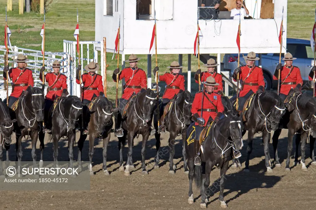 Royal Canadian Mounted Police Musical Ride RCMP cavalry in full dress red serge uniform on horseback holding lances with red and white pennons and commanding officer with sword drawn Mounties put on riding displays across Canada and around the world.Canada Alberta Lethbridge