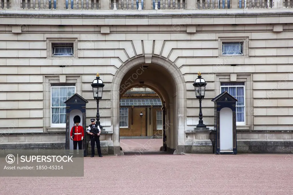 Westminster Buckingham Palace exterior with both Queens Guard and Metropolitan Police armed officers, England London