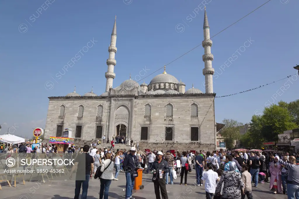 Eminonu Yeni Camii New Mosque with people selling goods to the tourists in the square outside.Turkey Istanbul