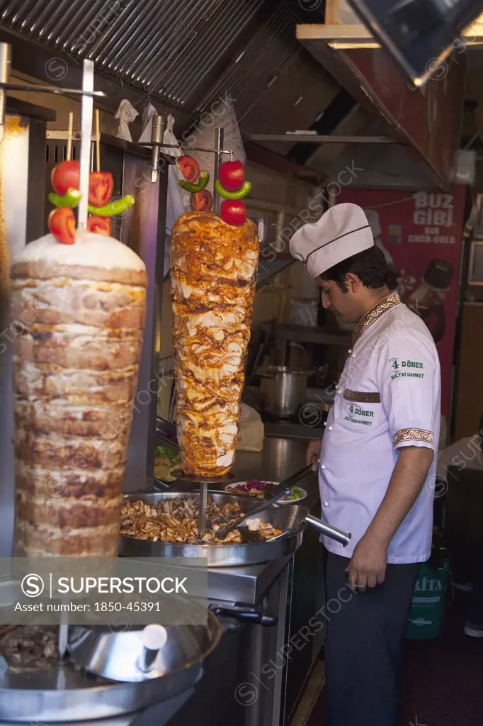 Sultanahmet man in kebab restaurant carving shawarma from skewered meats.Turkey Istanbul
