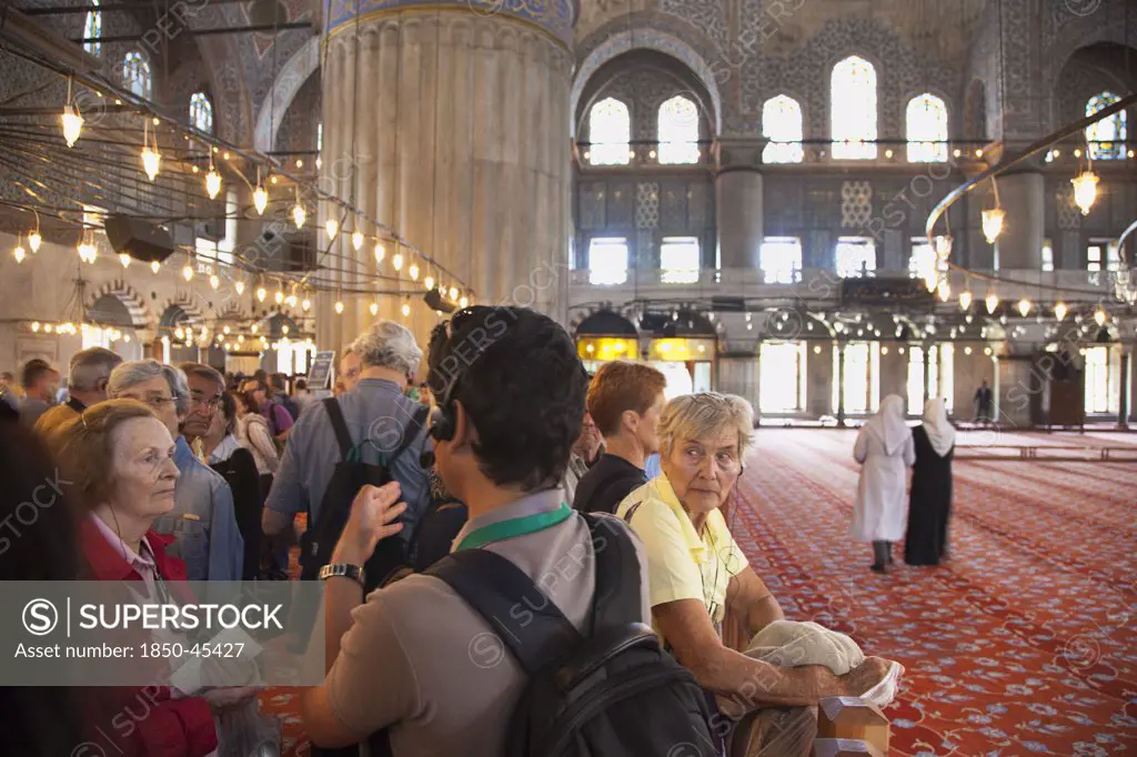 Sultanahmet Camii Blue Mosque interior with guided tour group listening on headphones to guide.Turkey Istanbul