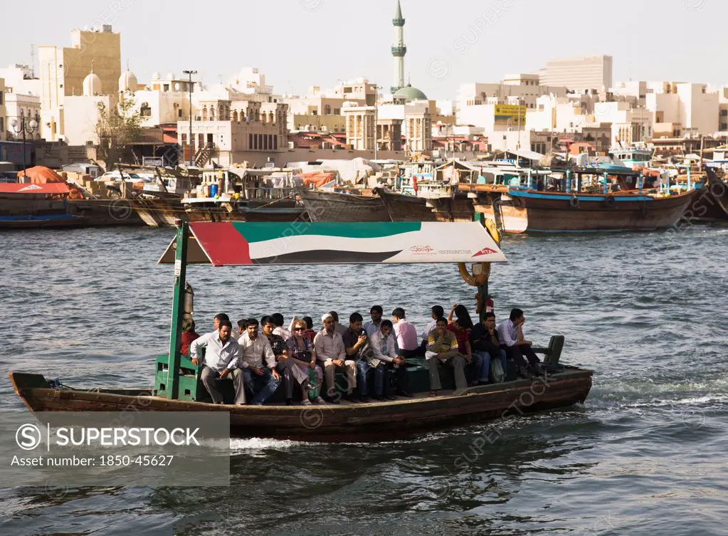 UAE , Dubai, Abra water taxi with commuters crossing the Creek Souk market behind.