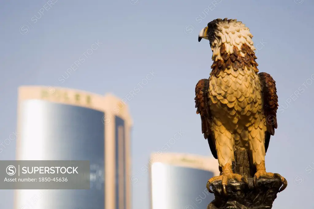 UAE , Dubai, Falcon ststue on the Creek with Twin Towers shopping mall behind.