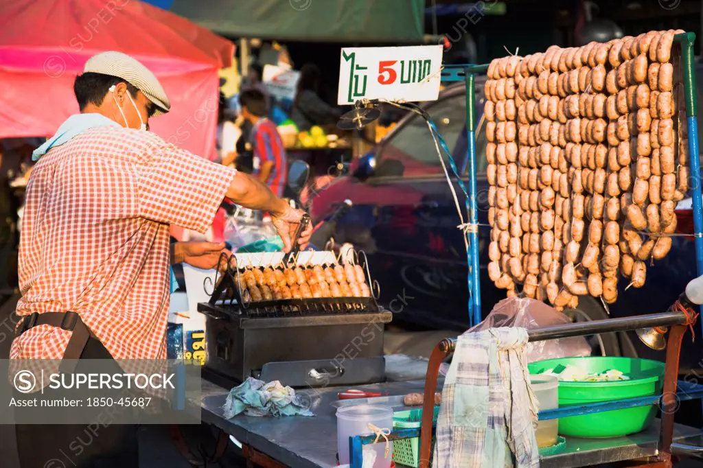 Thailand, Bangkok, Street vendor selling sausages in early evening light, 5 Baht each, cheapest food in the city.