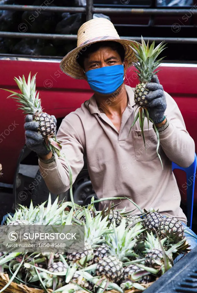 Thailand, Bangkok, Thai worker in mask against pollution packing Pineapple in Chinatown market.
