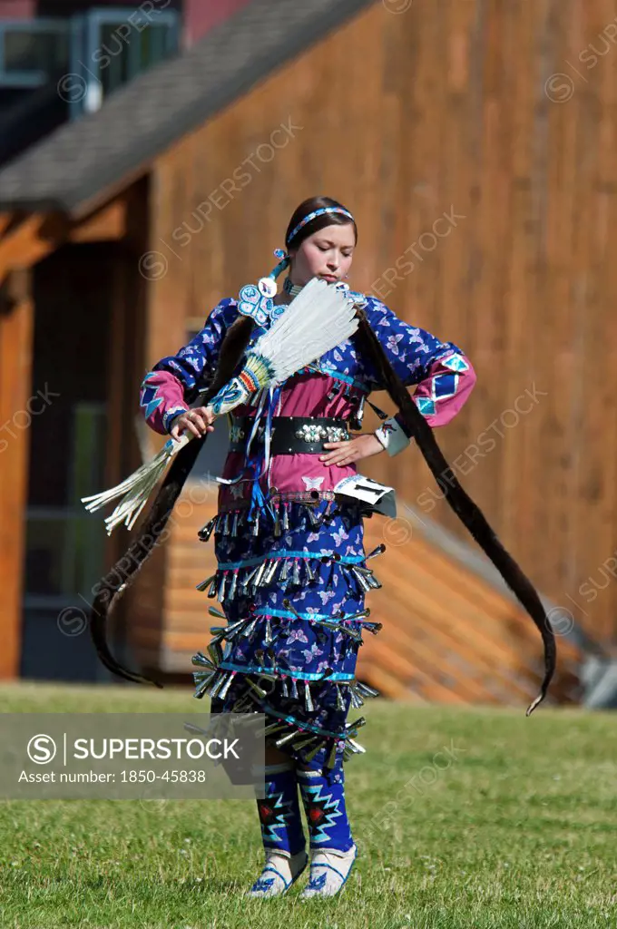 Canada, Alberta, Waterton Lakes National Park, Blackfoot dancer dressed in blue outfit with silver bells with long otter fur stole and white featherfanon tip-toes in the Jingle Dance at the Blackfoot Arts & Heritage Festival Pow Wow organized by Parks Canada and the Blackfoot Canadian Cultural Society.