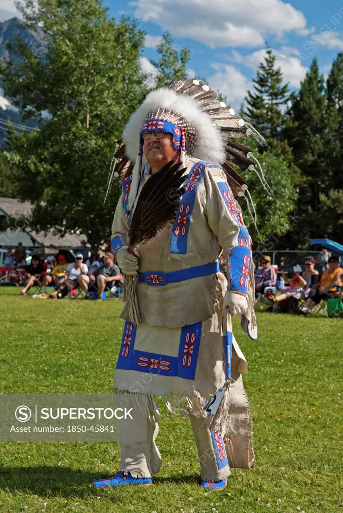 Canada, Alberta, Waterton Lakes National Park, Buckskin Dance at the Blackfoot Arts & Heritage Festival Pow Wow organized by Parks Canada and the Blackfoot Canadian Cultural Society, This dance is only for Blackfoot Chiefs and Elders and is a slow war dance, Blue sky with white clouds, Tourists in lawn chairs watching spectacle.