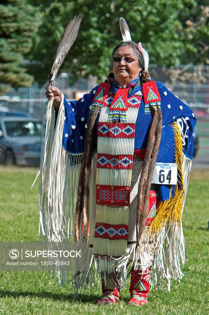 Canada, Alberta, Waterton Lakes National Park, Blackfoot dancer in blue cape trimmed withotter fur and porcupine quill apron holding a feather fan in the Women's Traditional Dance at the Blackfoot Arts & Heritage Festival Pow Wow organized by Parks Canada and the Blackfoot Canadian Cultural Society, UNESCO World Heritage Site.