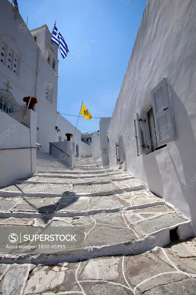 Greece, Cyclades, Islands, Sifnos Island, Apollonia Town, Portrait format low angle photograph of a typical alley found only at Cyclades island complex with the church of Agios Spyridonas on the left hand side.