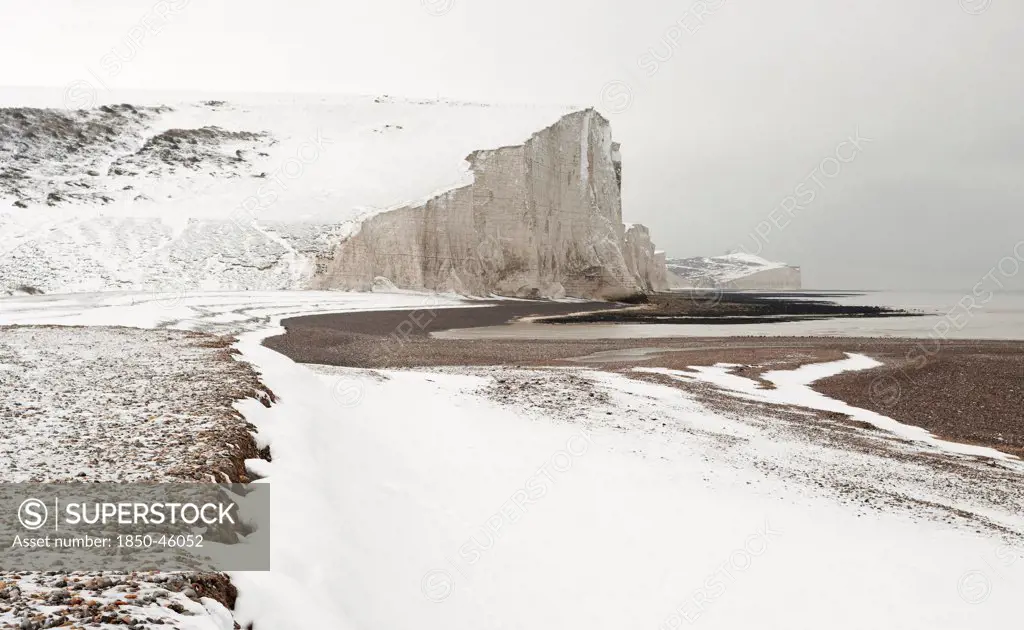 England, East Sussex, Seven Sisters, Snow covered chalk cliffs viewed from the coastguard cottages at Cuckmere Haven.
