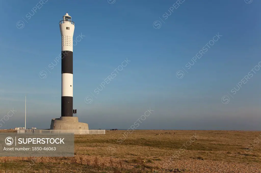 England, Kent, Romney Marsh, Dungeness, Black and white painted lighthouse on the shingle beach.