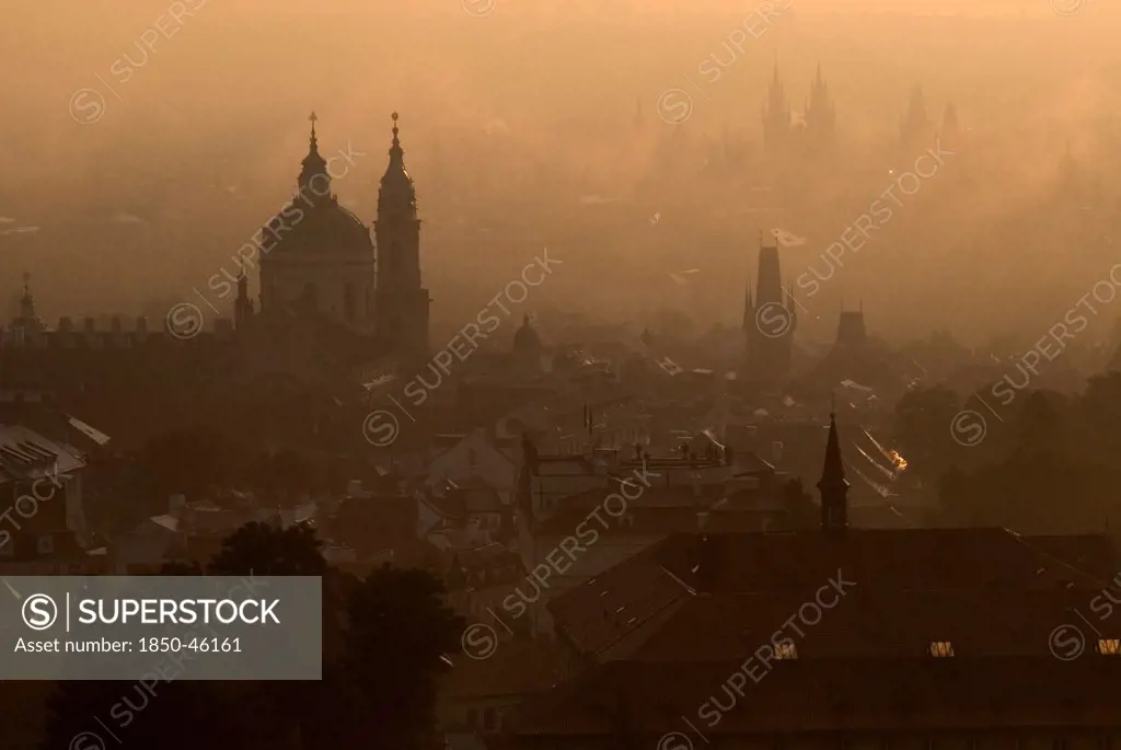 Czech Republic, Bohemia, Prague, Post dawn fog over the city with St Nicholas Cathedral in foreground.