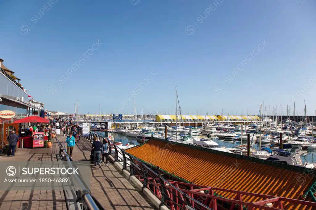 England, East Sussex, Brighton, View along the boardwalk over boats moored in the Marina.