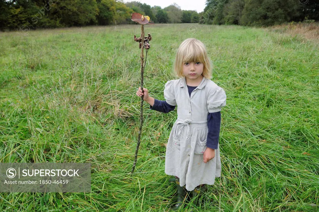Kids, Outdoor, 5 year old Eva with stick & leaf flag in a field of grass.