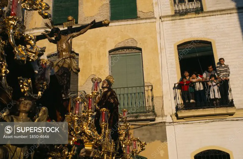 Spain, Andalucia, Seville, Semana Santa Easter Procession With A Family Watching From Balcony