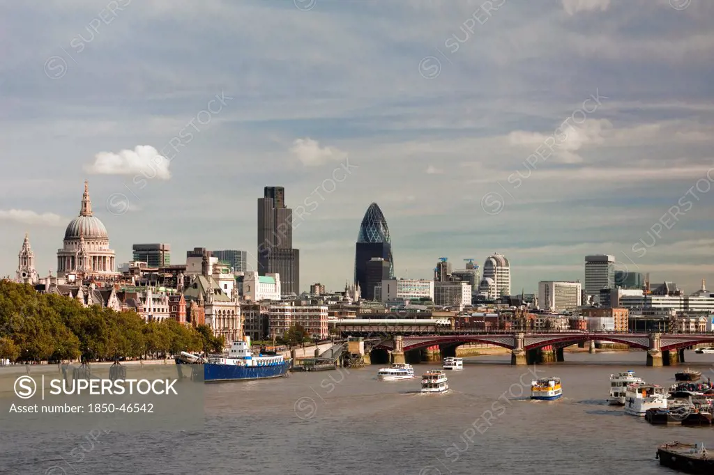 England, London, Skyline with view across the Thames towards Blackfriars Bridge from left to right St Pauls Cathedral Tower 42 and Swiss Re Tower. Boats on the water in the foreground.