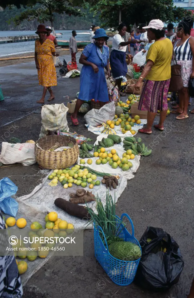 St Lucia, Soufriere, Fruit and vegetable vendors and customers at roadside market. Yams oranges soursop and limes amongst produce for sale.