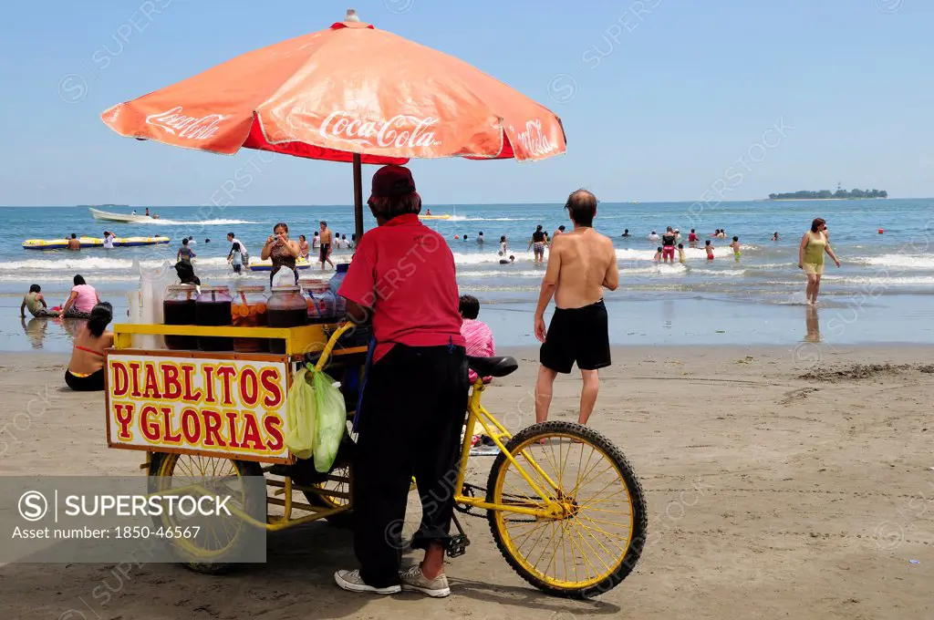 Mexico, Veracruz, Snack seller on Playa Villa del Mar with people on beach and in sea.