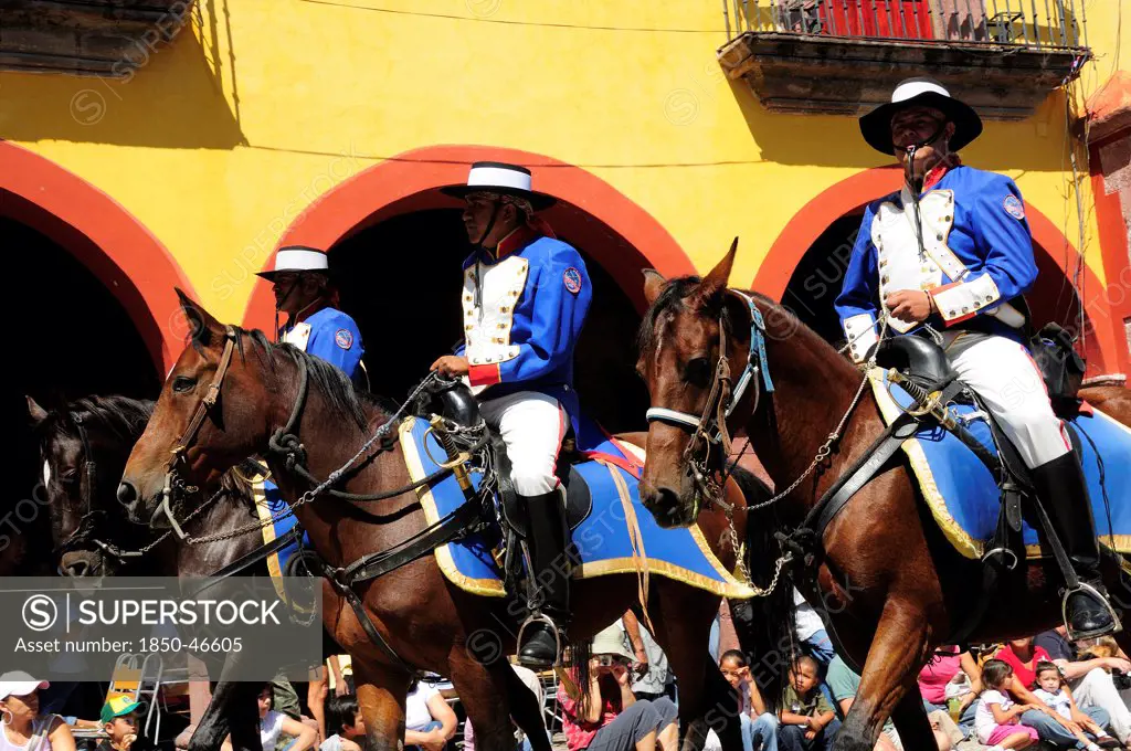 Mexico, Bajio, San Miguel de Allende, Independence Day celebrations. Re-enactment of the Call for Independence horsemen ride through street with watching crowd.
