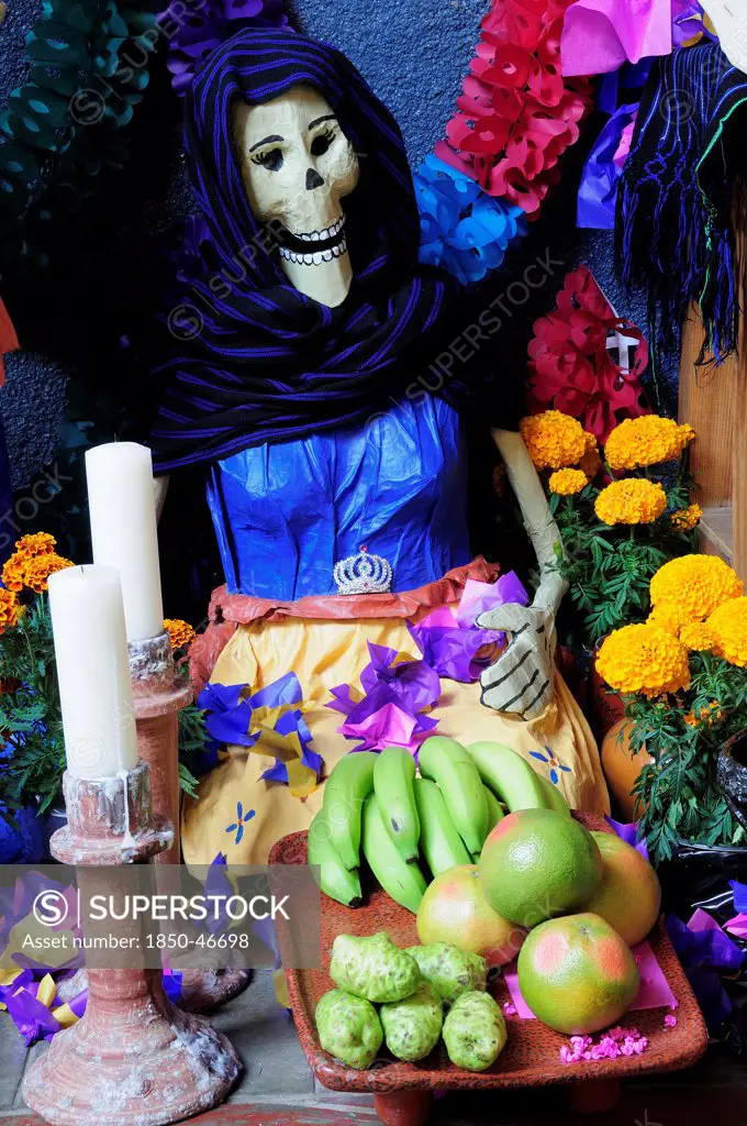 Mexico, Michoacan, Patzcuaro, Dia de los Muertos Day of the Dead altar with figures food candles and flowers.