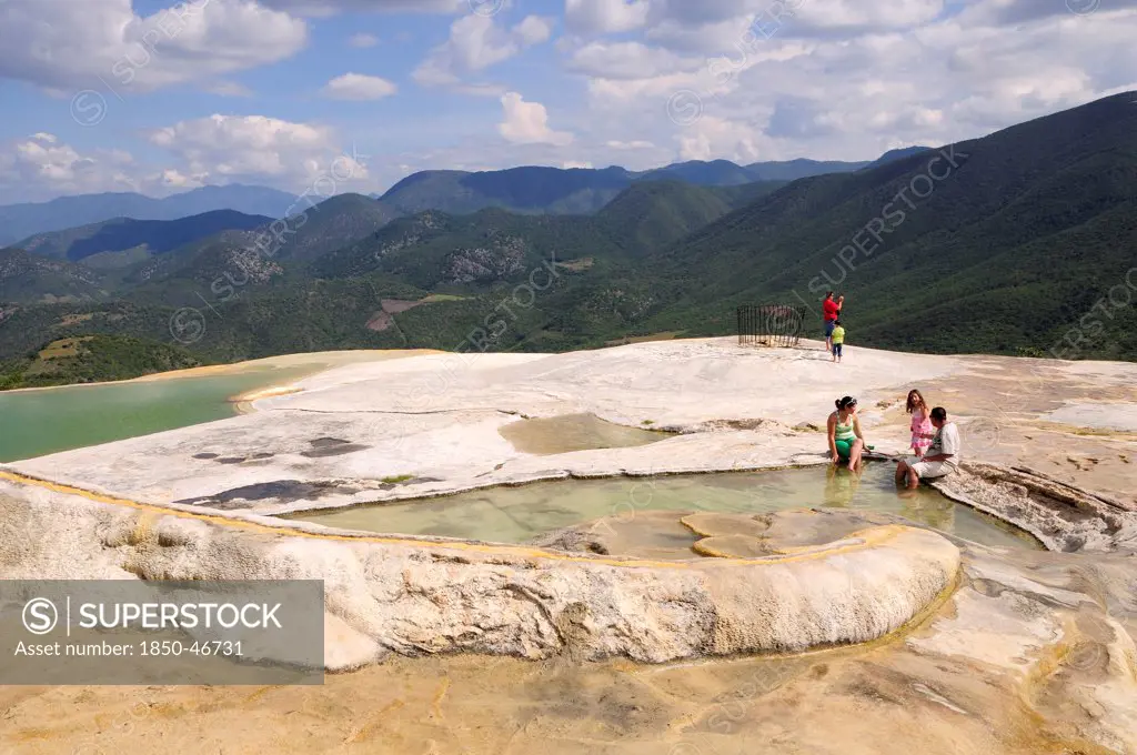 Mexico, Oaxaca, Hierve el Agua, Tourists beside limestone pools and looking out over surrounding countryside.