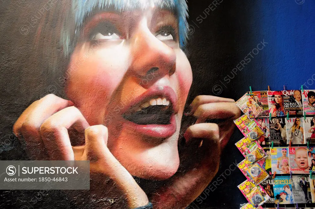 Mexico, Federal District, Mexico City, Condesa District Wall painting detail depicting face of young woman looking upwards with chin in hands with magazine stall at side.