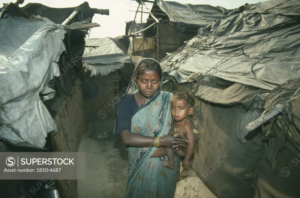 India, Delhi, Woman Holding Small Child In Slum Housing Area