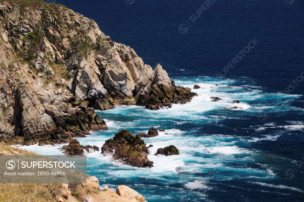 Mexico, Oaxaca, Huatulco, Waves breaking against rocky coastline.