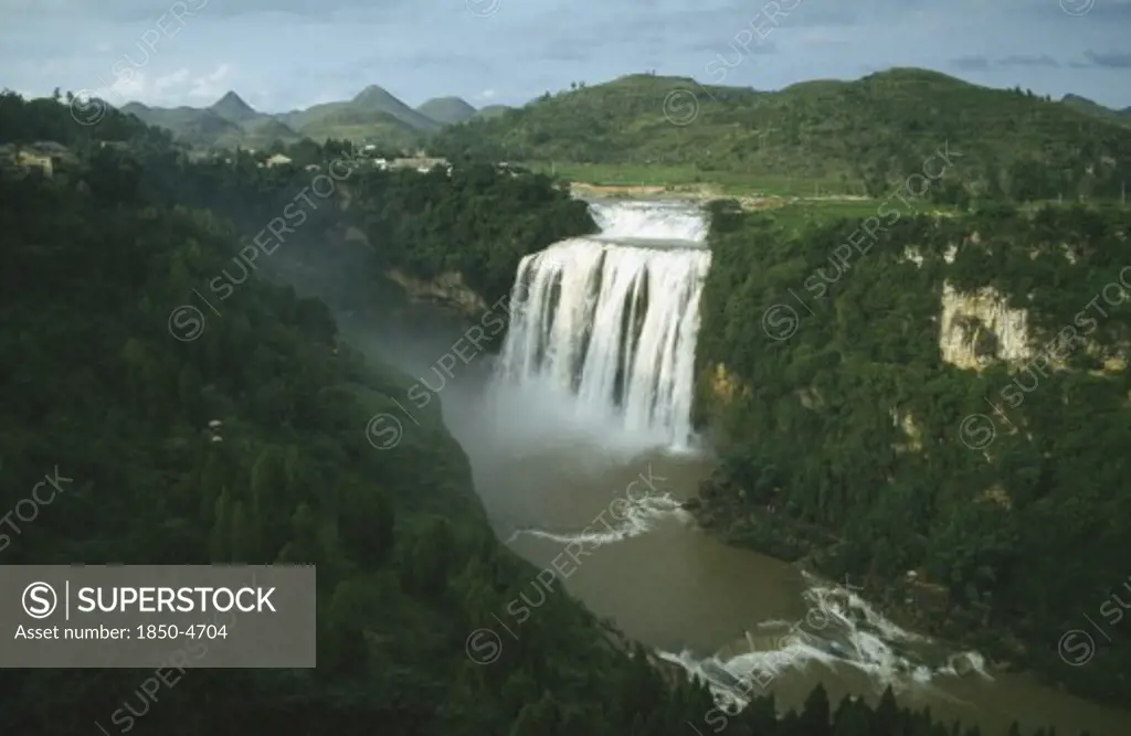 China, Guizhou, Huangguoshu Falls Seen From A Distance Within Lush Green Surrounding Landscape