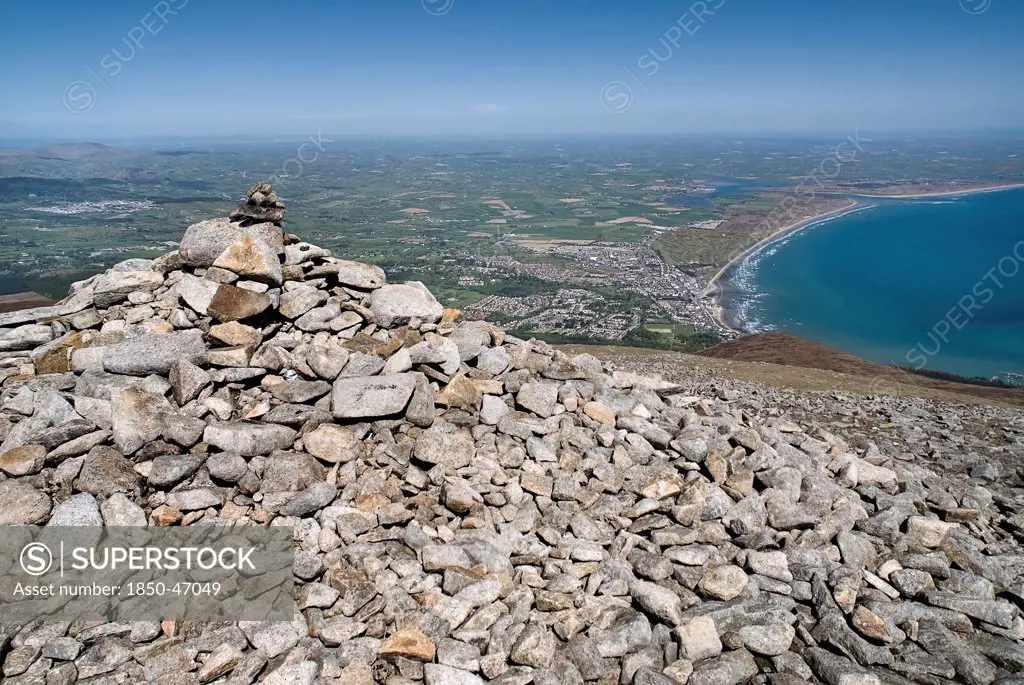 Ireland, County Down, Mourne Mountains, A cairn on the summit of Slieve Donard with Newcastle and its beach in the background