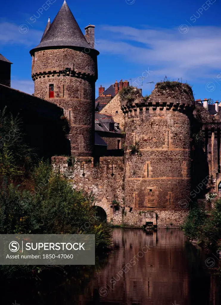 France, Bretagne, Ille-et-Vilaine, Fougeres. Defensive walls and towers of the chateau dating from 11th to15th centuries rising from moat with blue sky beyond.