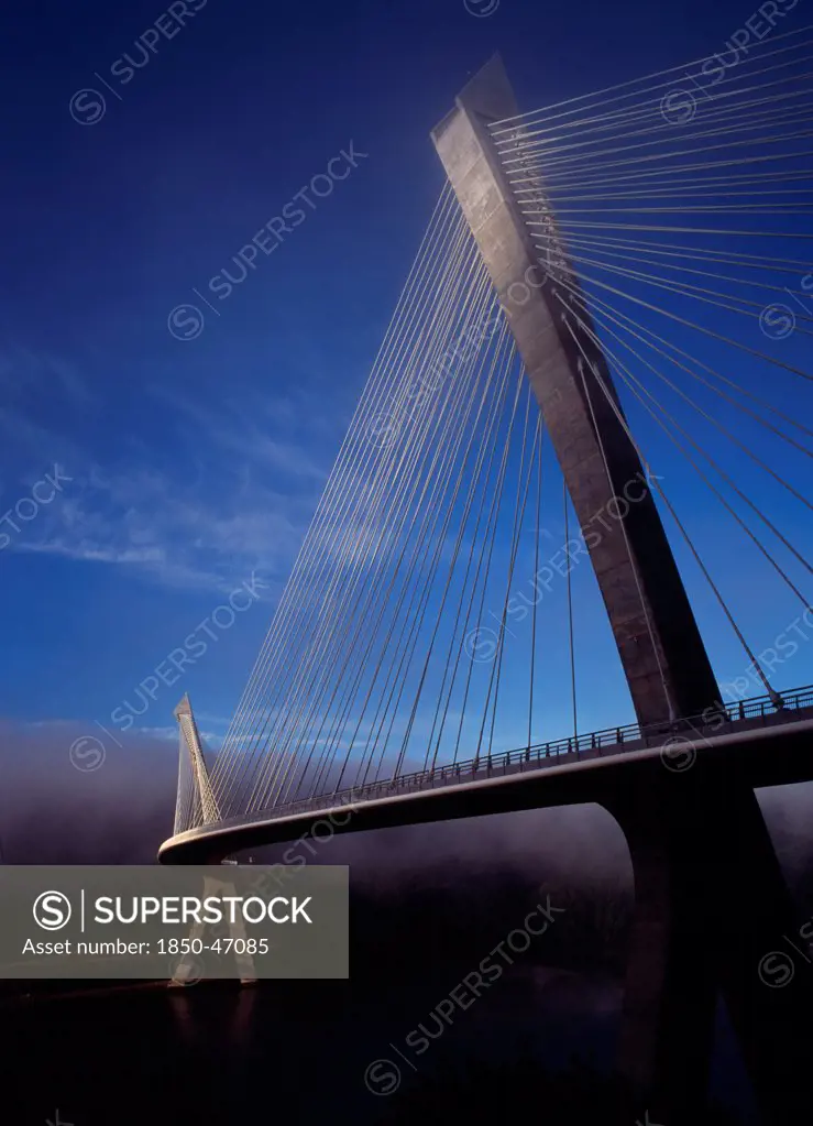 France, Bretagne, Finistere, Ile de Crozon. View of the new Pont de Terenez suspension bridge opened April 2011 from north bank of the River Aulne in early morning fog.